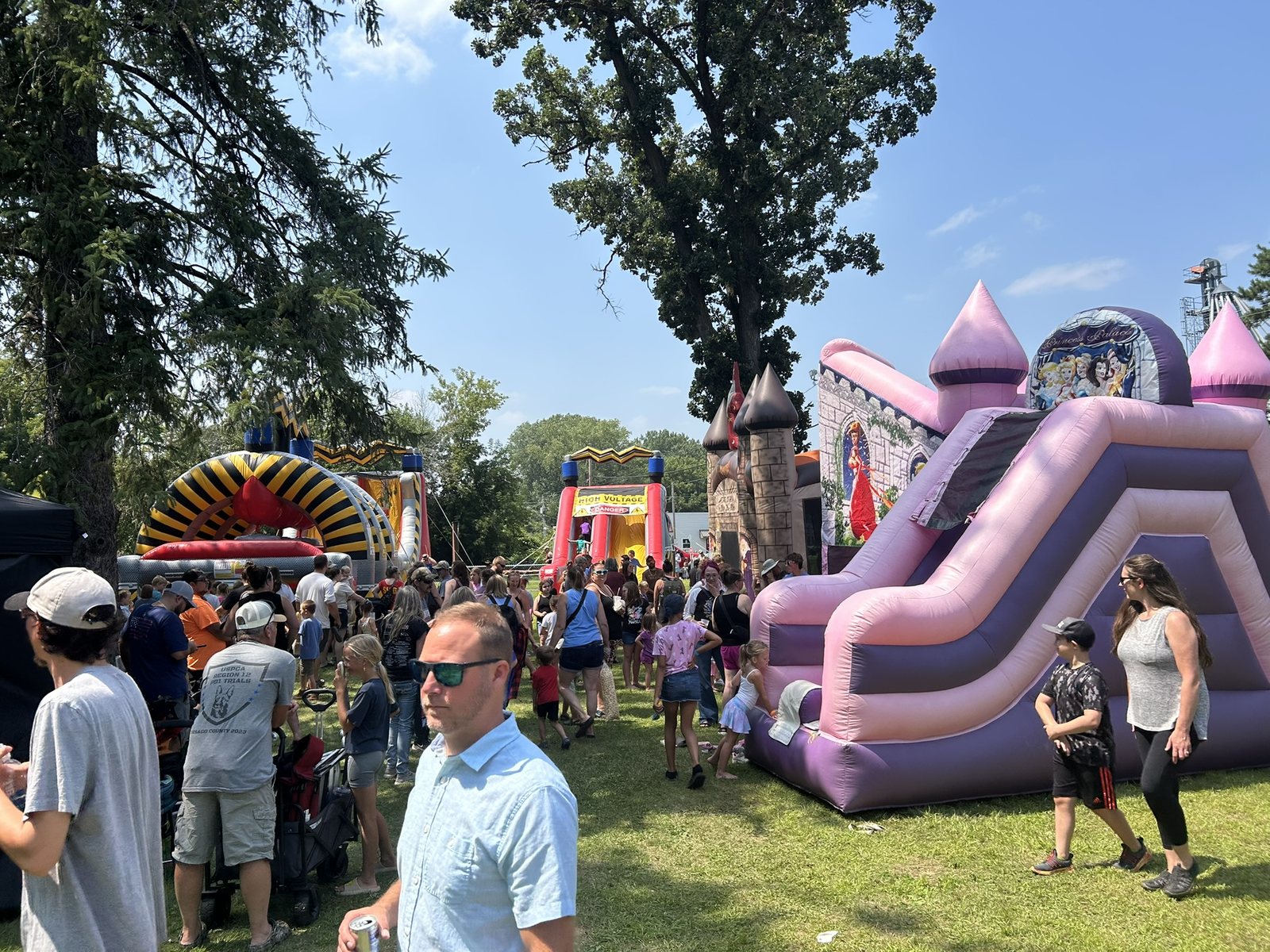 A large crowd enjoying multiple State of Fun attractions at a family festival