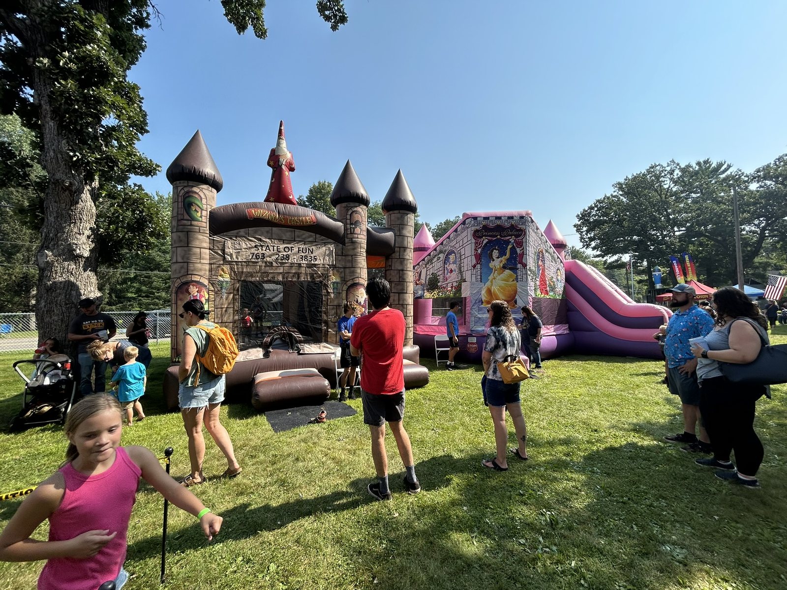 Families enjoying castle-themed inflatable attractions at a community festival