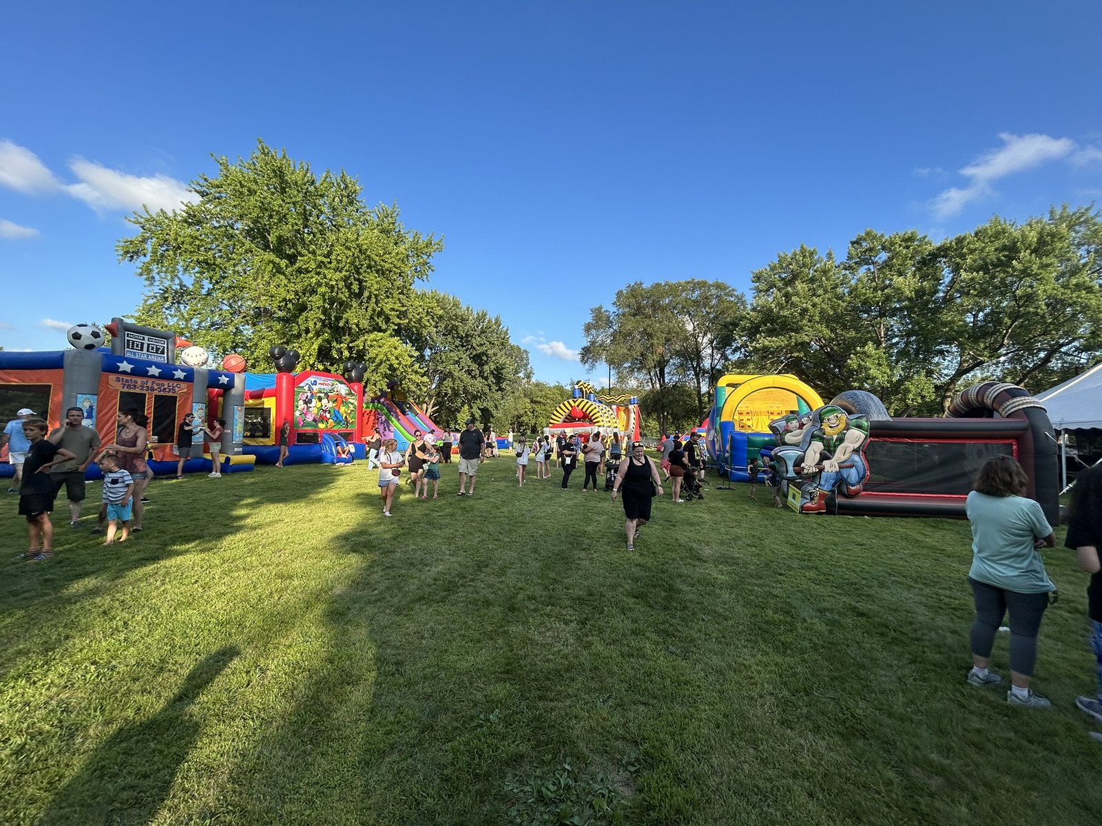Families walking among a wide selection of inflatables at an outdoor festival