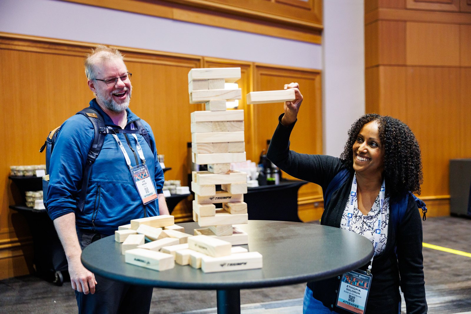 Corporate event attendees laughing while playing a giant block-stacking game
