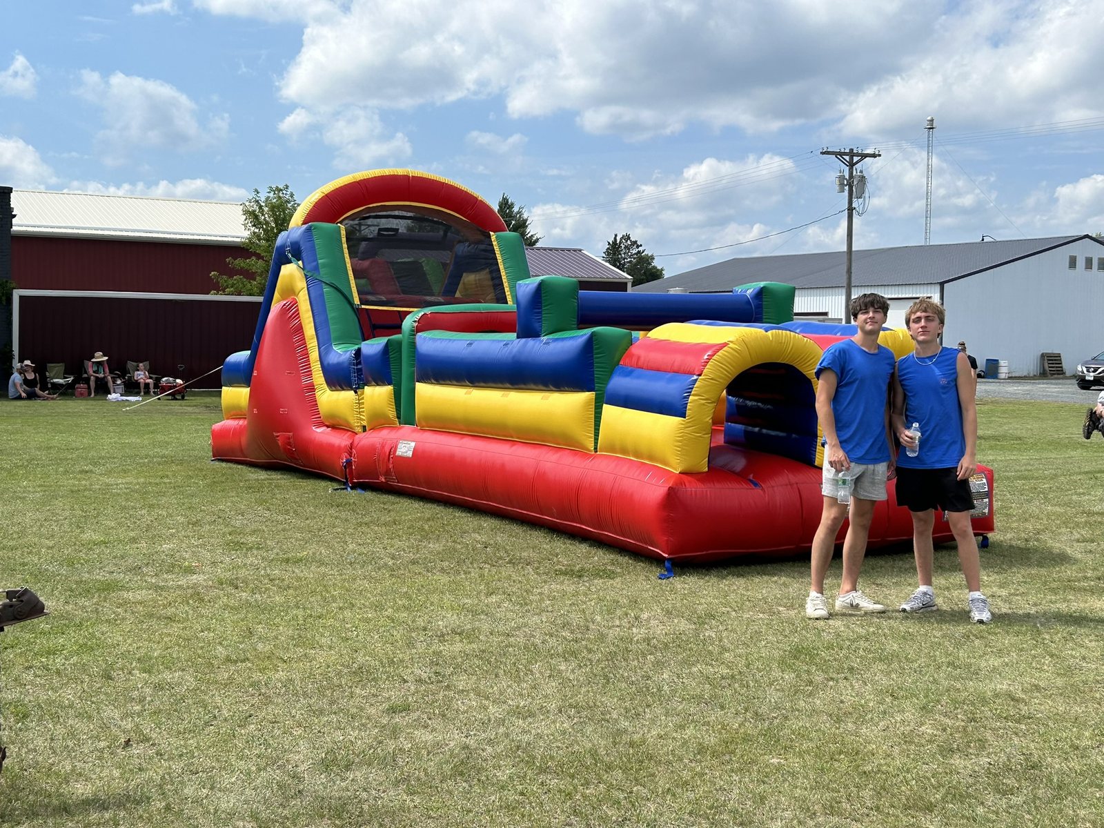 Teen guests standing beside a colorful inflatable obstacle course