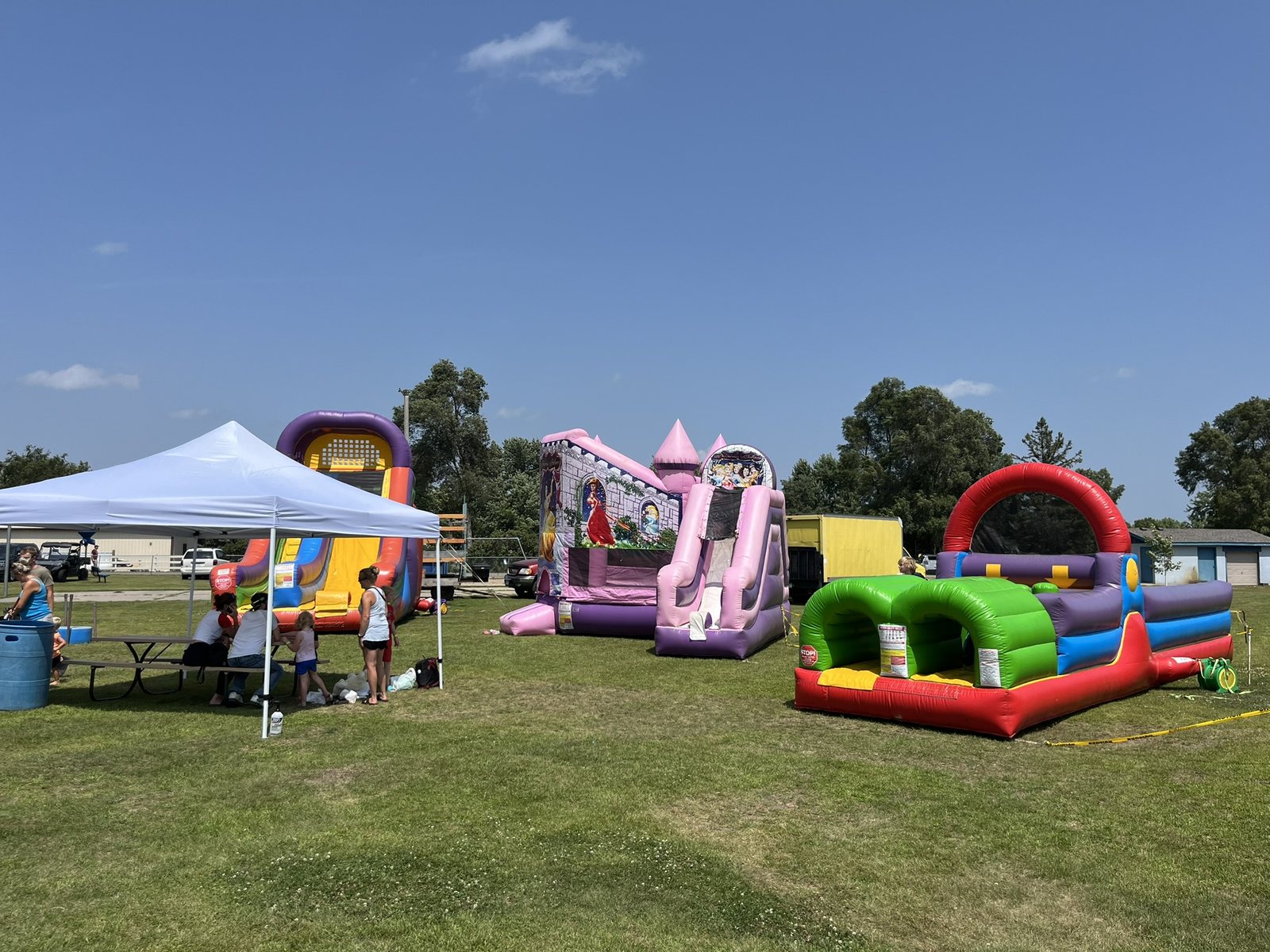 Multiple inflatable attractions and tents arranged for an outdoor party